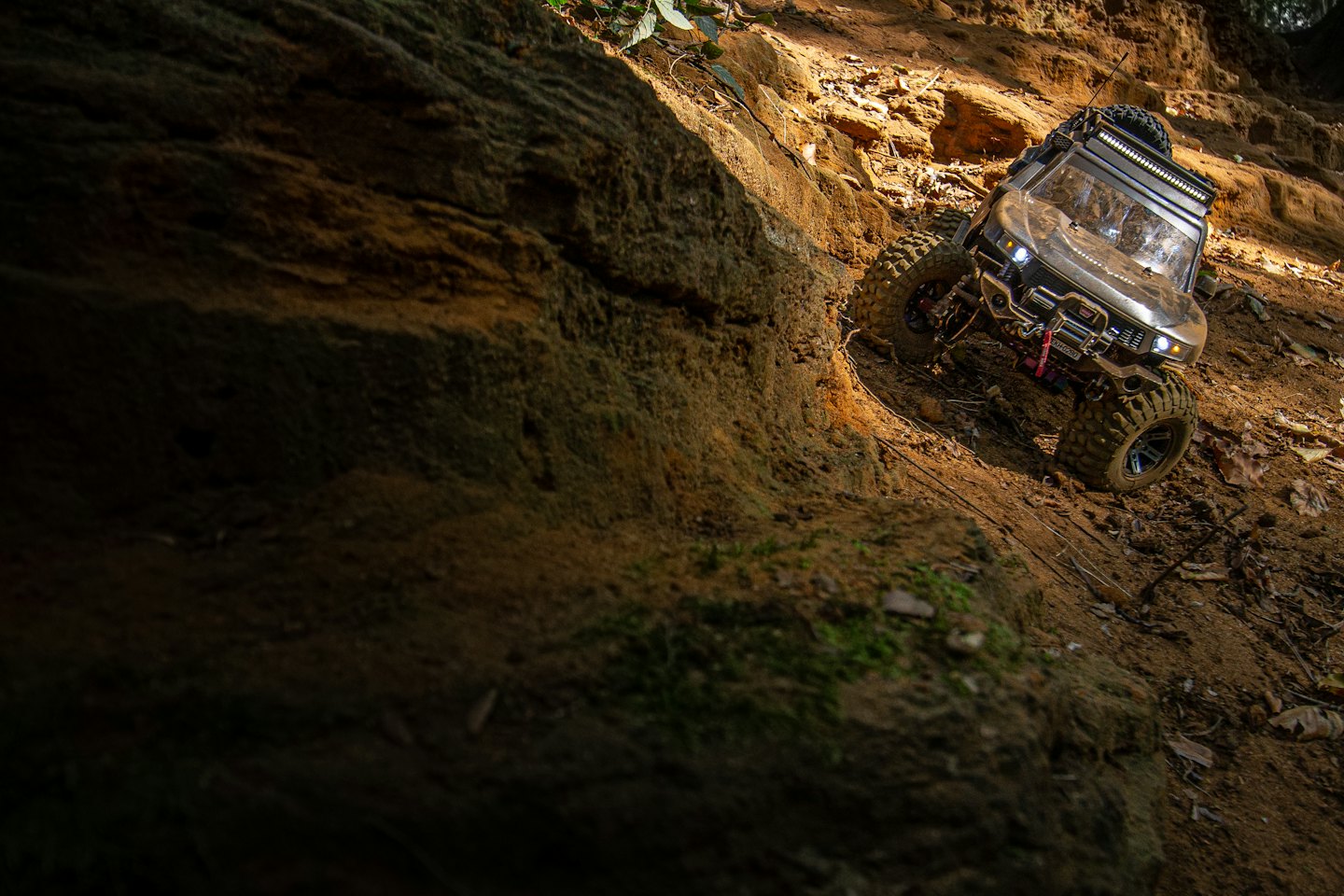 Remote-controlled truck climbing a muddy, rocky hill.