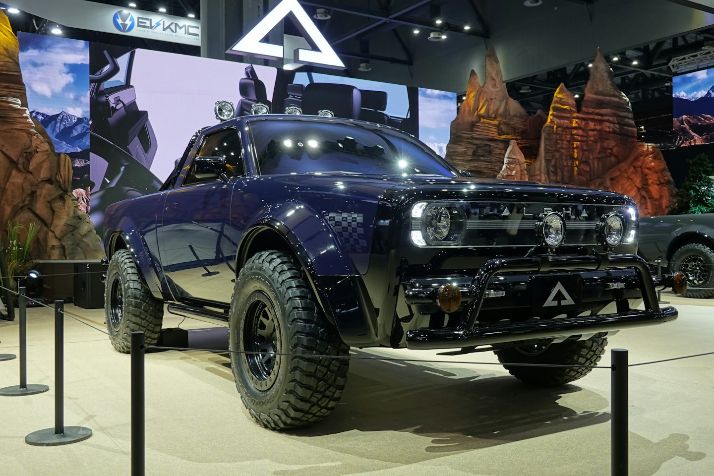 Dark blue electric pickup truck at an indoor exhibition booth.