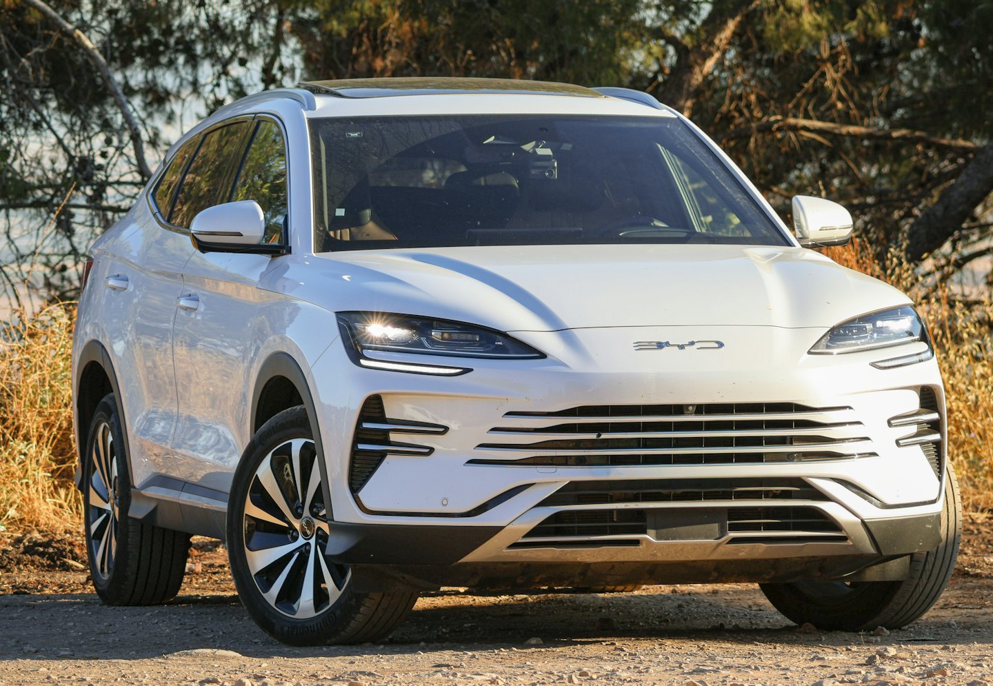White electric SUV parked on a dusty dirt road.