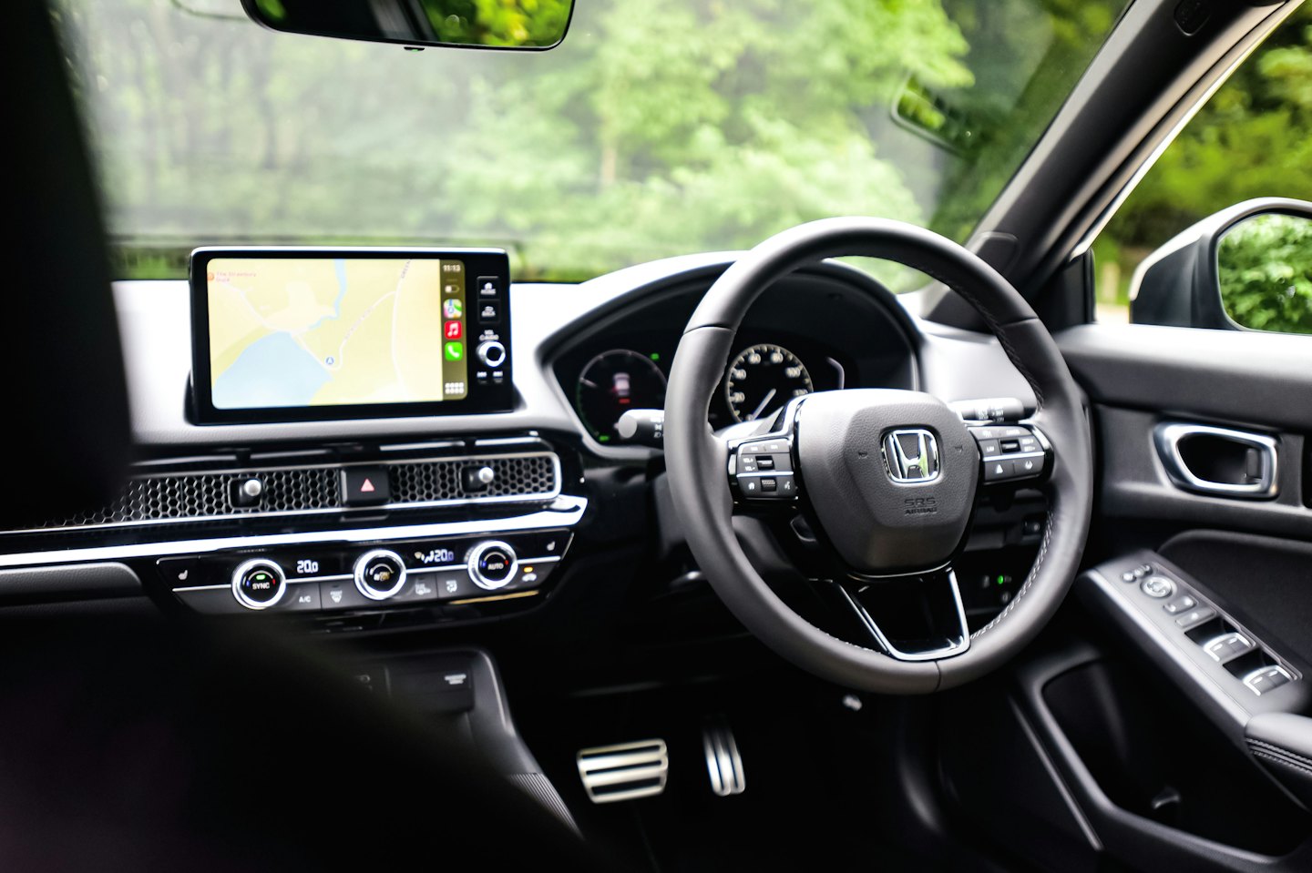 Modern car dashboard with digital screen and leather steering wheel.